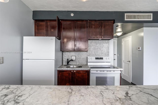 kitchen with light stone counters, tasteful backsplash, sink, electric range oven, and stainless steel fridge