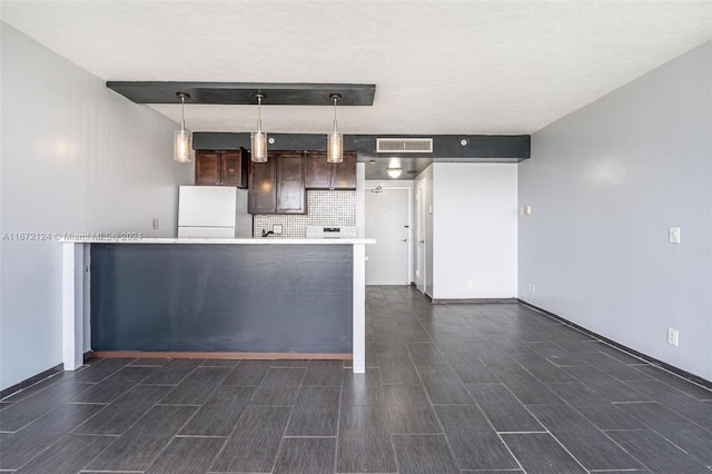 kitchen with dark brown cabinetry, hanging light fixtures, white fridge, dark hardwood / wood-style flooring, and decorative backsplash