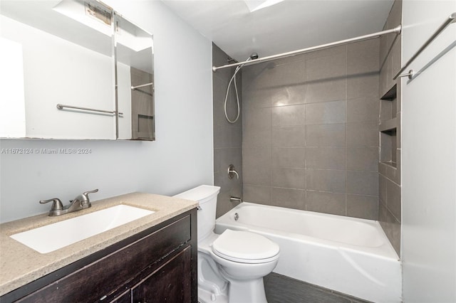 full bathroom featuring tiled shower / bath, vanity, and toilet