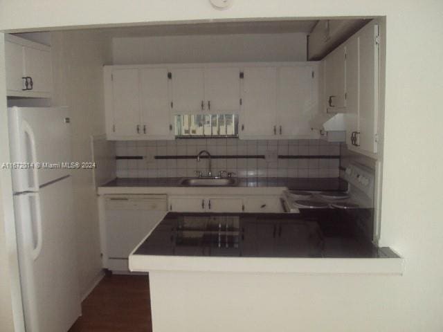 kitchen with kitchen peninsula, backsplash, white appliances, sink, and white cabinets