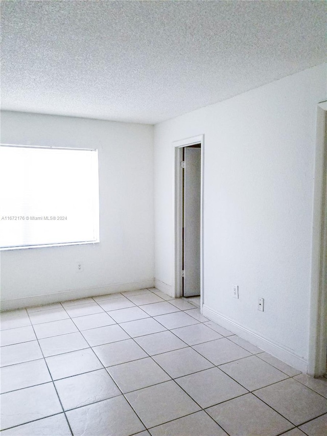 unfurnished room featuring light tile patterned floors and a textured ceiling