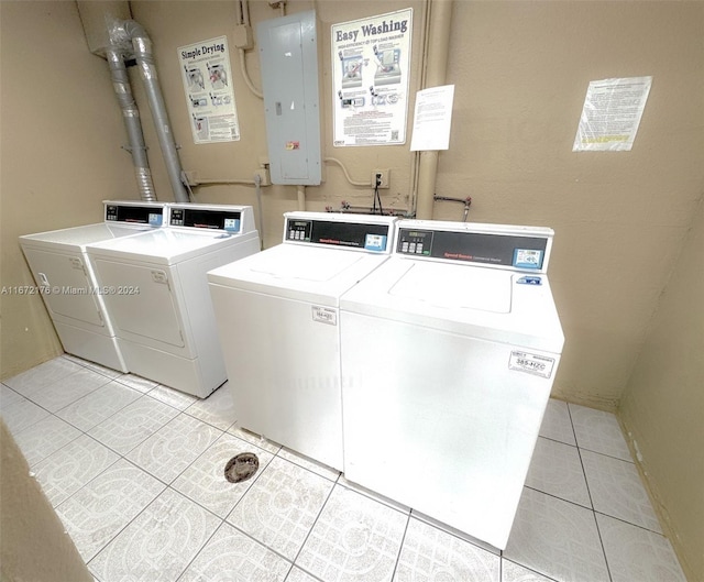 laundry room featuring light tile patterned floors, electric panel, and washing machine and clothes dryer