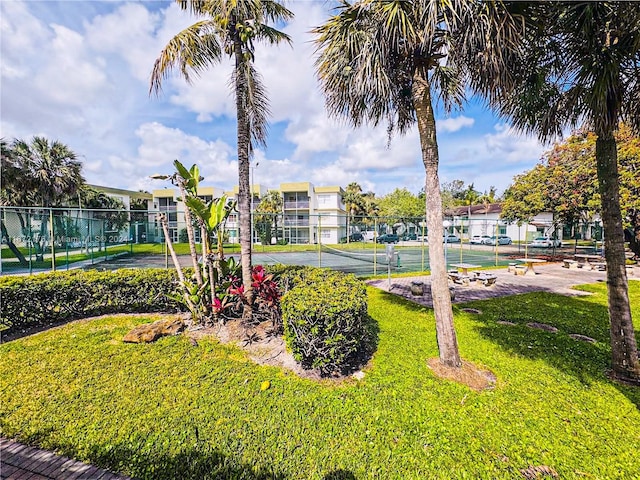 view of home's community featuring a lawn and tennis court