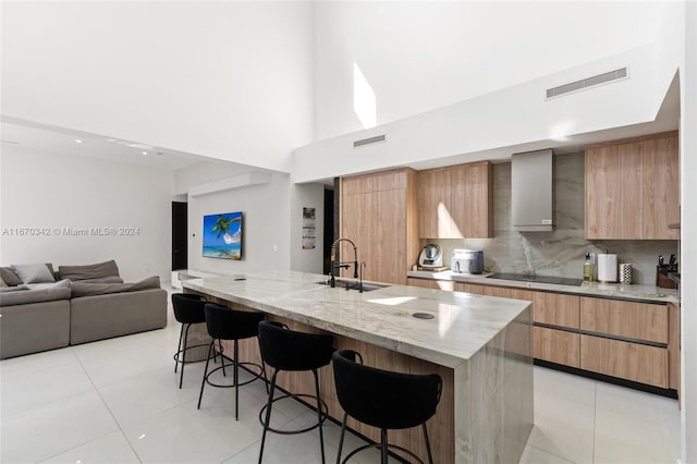 kitchen with light stone counters, an island with sink, a kitchen breakfast bar, and sink