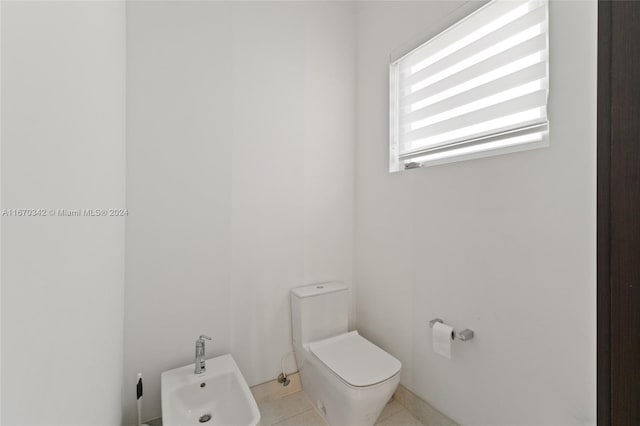 bathroom featuring tile patterned flooring, toilet, and a bidet