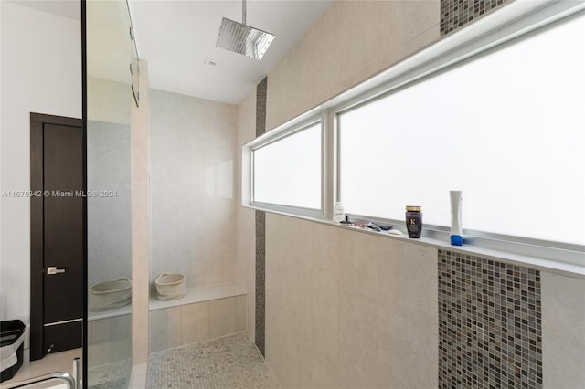 bathroom with a tile shower and tile patterned flooring