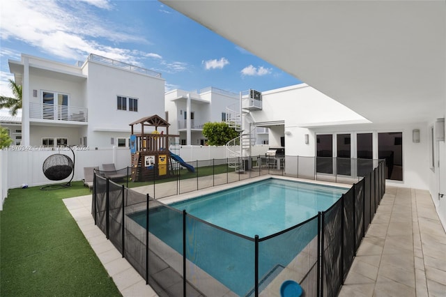 view of swimming pool featuring a playground, a lawn, and a patio area