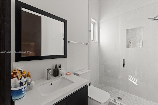 bathroom featuring a shower with door, toilet, and vanity