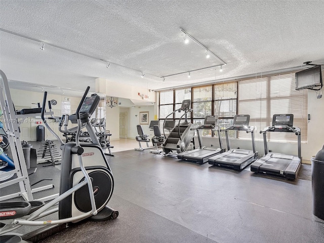 workout area with track lighting and a textured ceiling