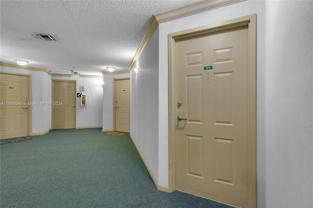 hall with a textured ceiling, carpet flooring, and ornamental molding