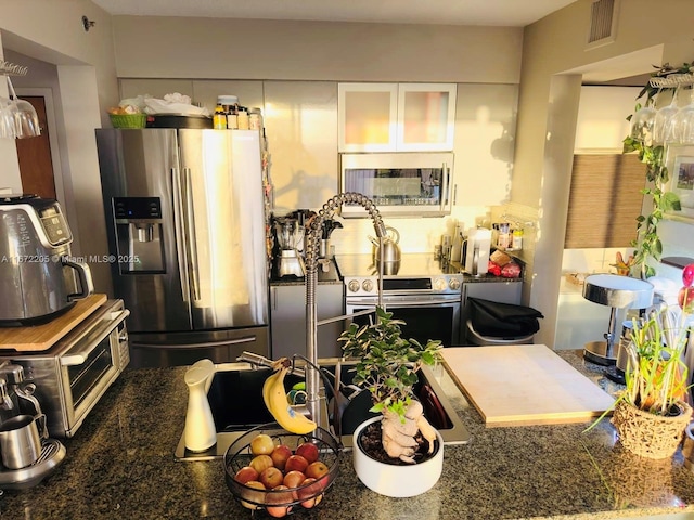 kitchen featuring a toaster, stainless steel appliances, visible vents, glass insert cabinets, and white cabinetry