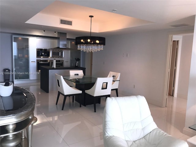 tiled dining room featuring a tray ceiling and a chandelier