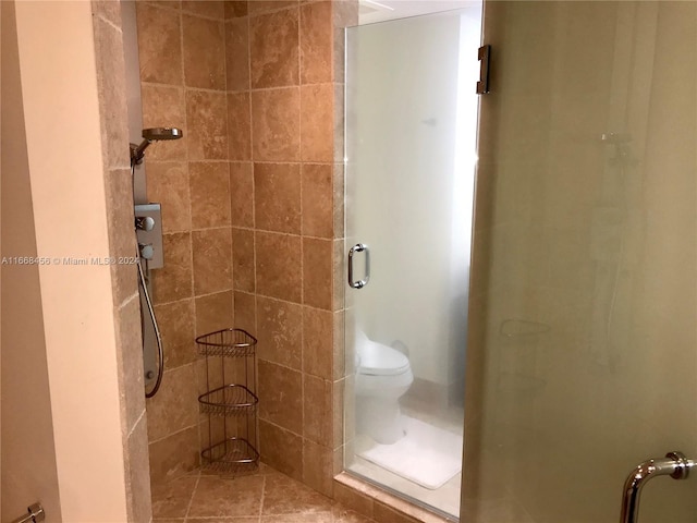 bathroom featuring a shower with door, tile patterned floors, and toilet