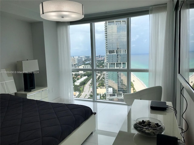 bedroom featuring a water view, light tile patterned floors, and expansive windows