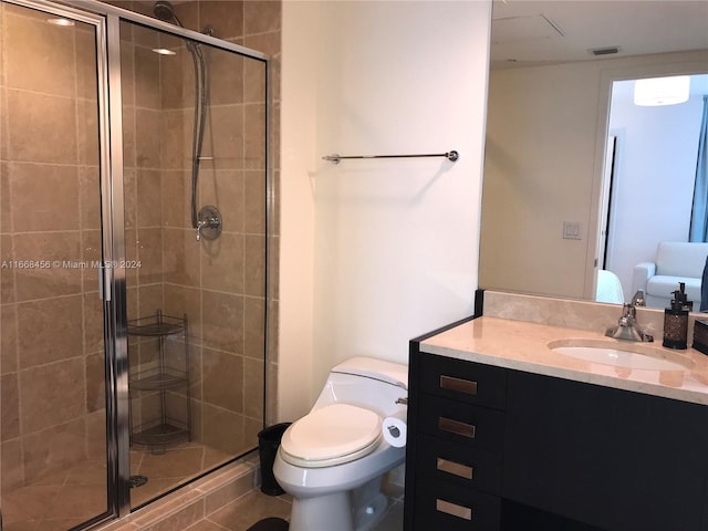 bathroom with vanity, a shower with shower door, toilet, and tile patterned floors