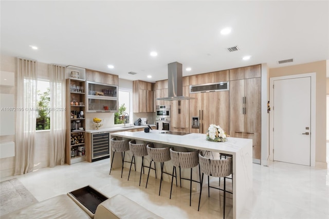 kitchen with sink, a kitchen island, beverage cooler, exhaust hood, and a kitchen breakfast bar