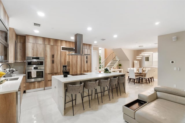 kitchen with a breakfast bar, ventilation hood, double oven, a center island, and cooktop