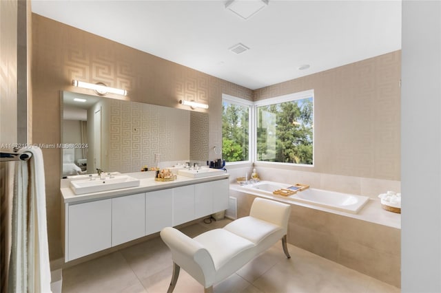 bathroom with a relaxing tiled tub, vanity, and tile patterned flooring