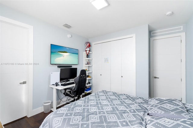 bedroom with dark hardwood / wood-style floors and a closet