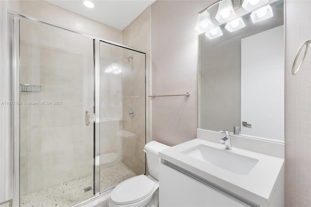 bathroom with a shower with door, vanity, and toilet