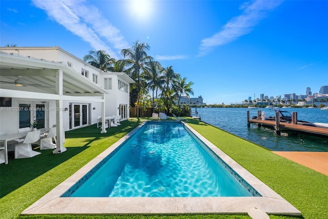 view of pool featuring french doors, a boat dock, a water view, and a lawn