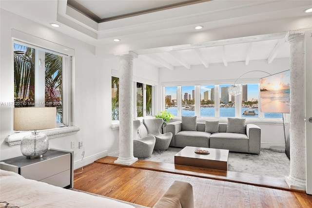 sunroom with plenty of natural light, beam ceiling, and decorative columns