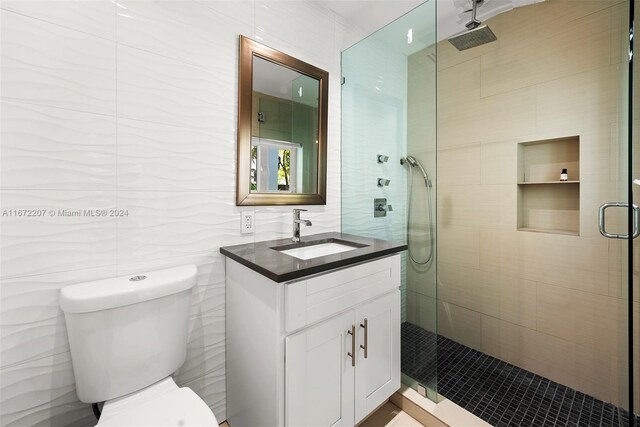 bathroom featuring tile walls, vanity, an enclosed shower, and toilet