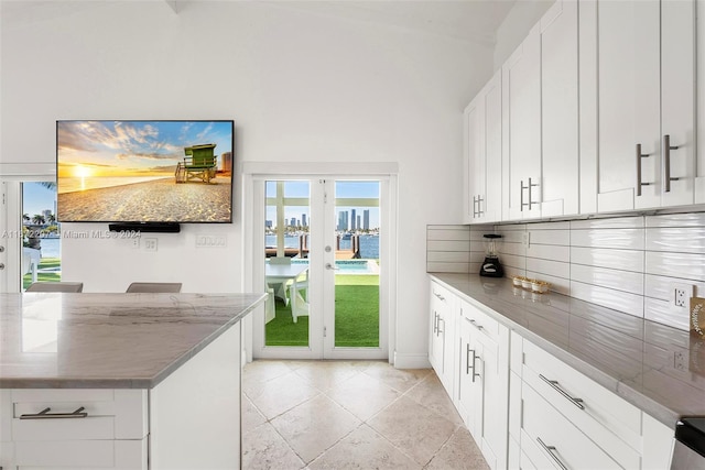 kitchen featuring french doors, white cabinetry, a healthy amount of sunlight, and light stone counters