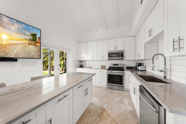 kitchen featuring sink, tasteful backsplash, light stone counters, white cabinets, and appliances with stainless steel finishes