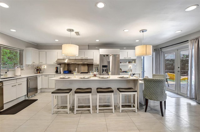 kitchen featuring white cabinetry, hanging light fixtures, appliances with stainless steel finishes, and a kitchen island