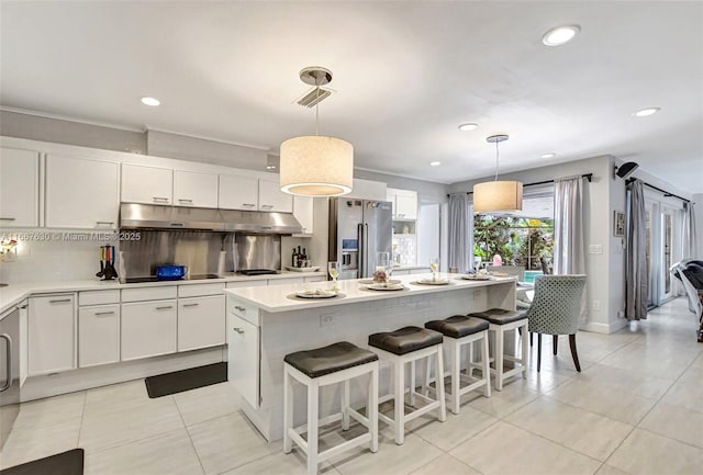 kitchen featuring pendant lighting, a kitchen island, white cabinetry, backsplash, and high end refrigerator