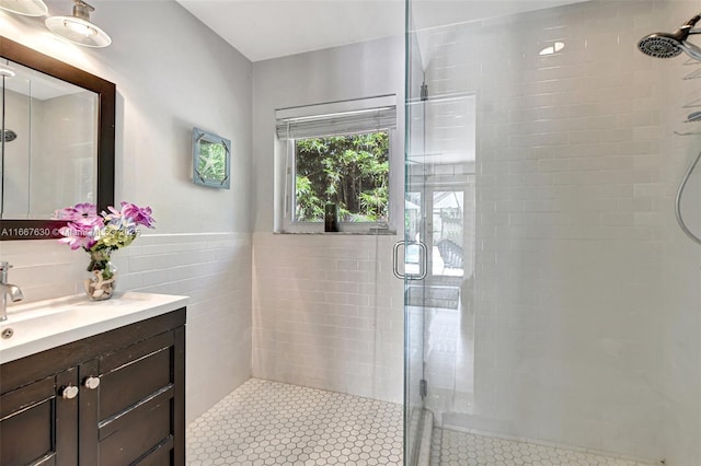 bathroom with vanity, a shower with shower door, and tile walls