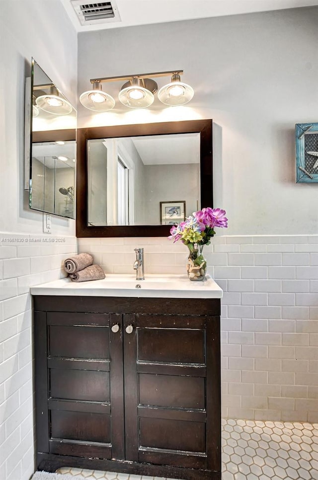 bathroom with vanity, a shower, and tile walls