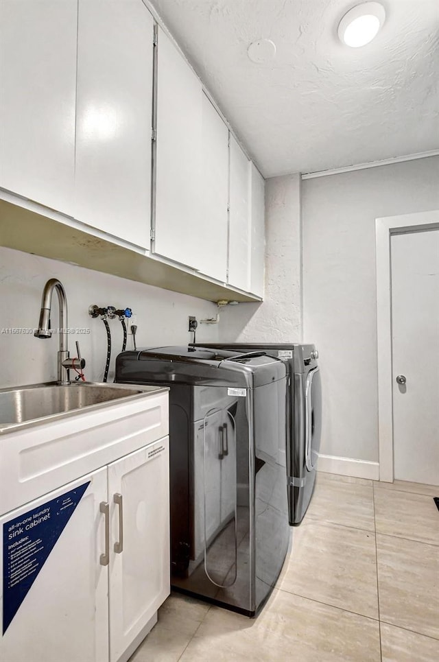 laundry area with sink, washer and dryer, light tile patterned floors, cabinets, and a textured ceiling