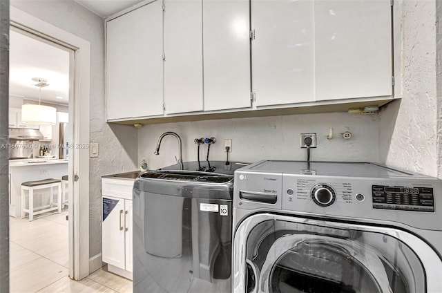 laundry room featuring separate washer and dryer, light tile patterned floors, and cabinets