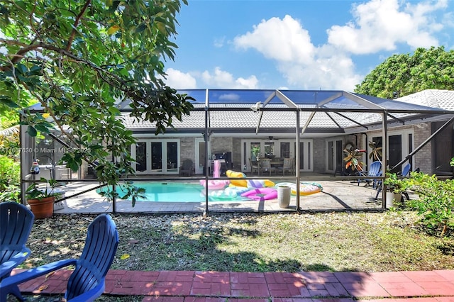 rear view of property with a patio area, a lanai, ceiling fan, and french doors