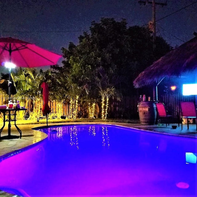 pool at night featuring a patio