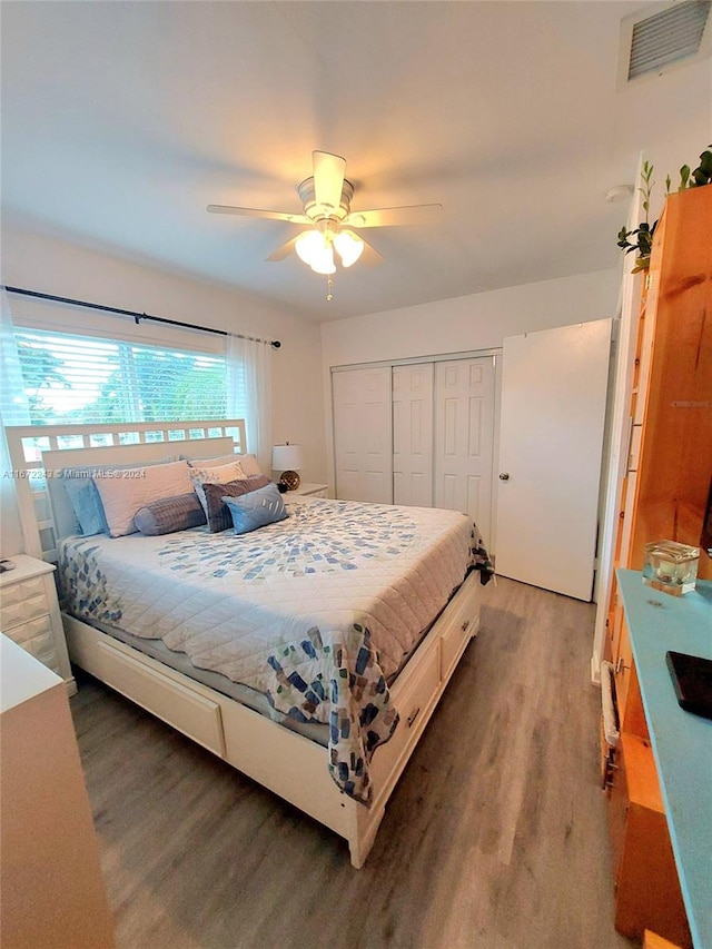 bedroom with dark hardwood / wood-style flooring, a closet, and ceiling fan