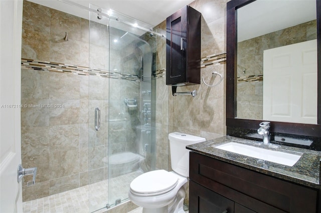 bathroom with tile walls, vanity, toilet, and walk in shower