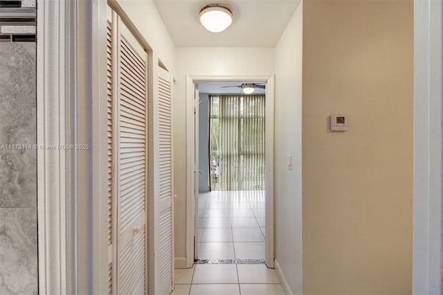 corridor featuring baseboards and light tile patterned flooring
