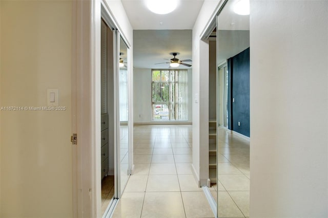 hall featuring light tile patterned floors and baseboards