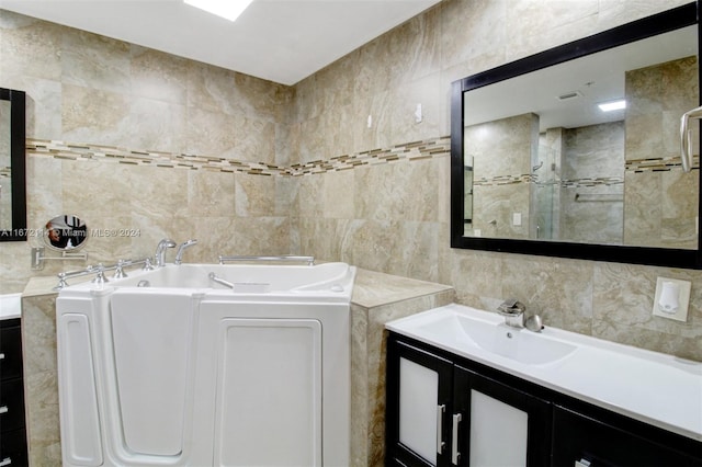 bathroom featuring tile walls, vanity, and a bath