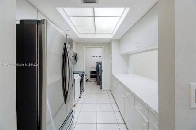 kitchen with white cabinets, independent washer and dryer, stainless steel appliances, and light tile patterned floors