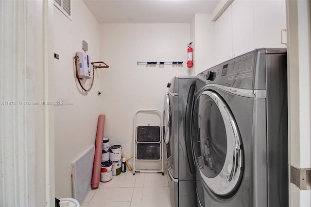 laundry area featuring separate washer and dryer, light tile patterned floors, and visible vents