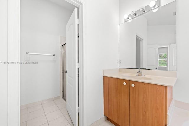 bathroom with a shower with door, vanity, and tile patterned floors