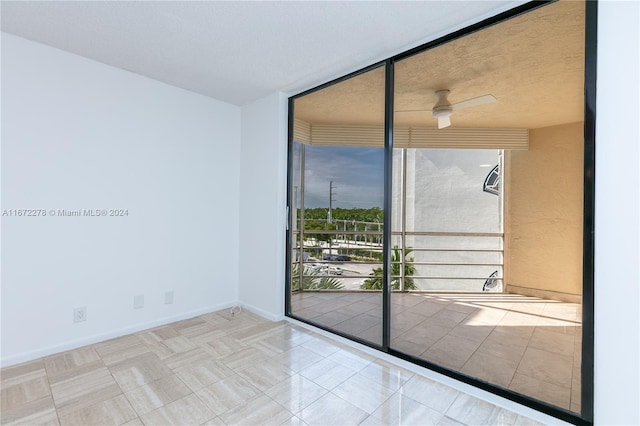 unfurnished room with ceiling fan and floor to ceiling windows