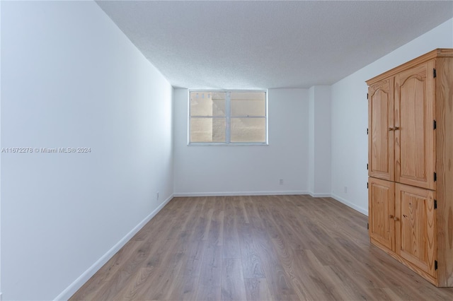 unfurnished room featuring a textured ceiling and light hardwood / wood-style flooring