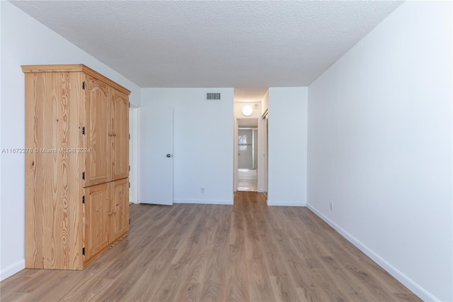 unfurnished room featuring light hardwood / wood-style flooring and a textured ceiling