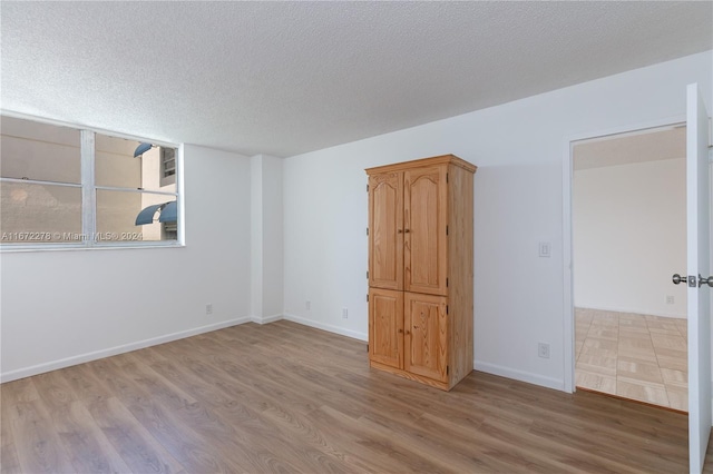 empty room with a textured ceiling and light wood-type flooring