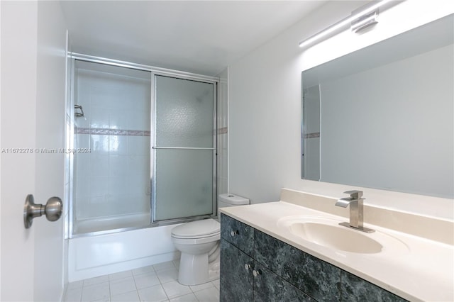 full bathroom with bath / shower combo with glass door, vanity, tile patterned flooring, and toilet